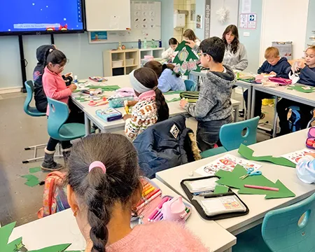 Kinder arbeiten in der Klasse an der Winterdekoration der Fenster