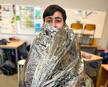 Schüler in eine Erste-Hilfe-Decke eingewickelt