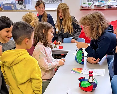 Schüler mit Unterrichtender und Arbeitsprodukt im Klassenraum