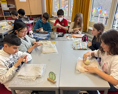 Kinder am Gruppentisch präsentieren ihre Arbeitsergebnisse